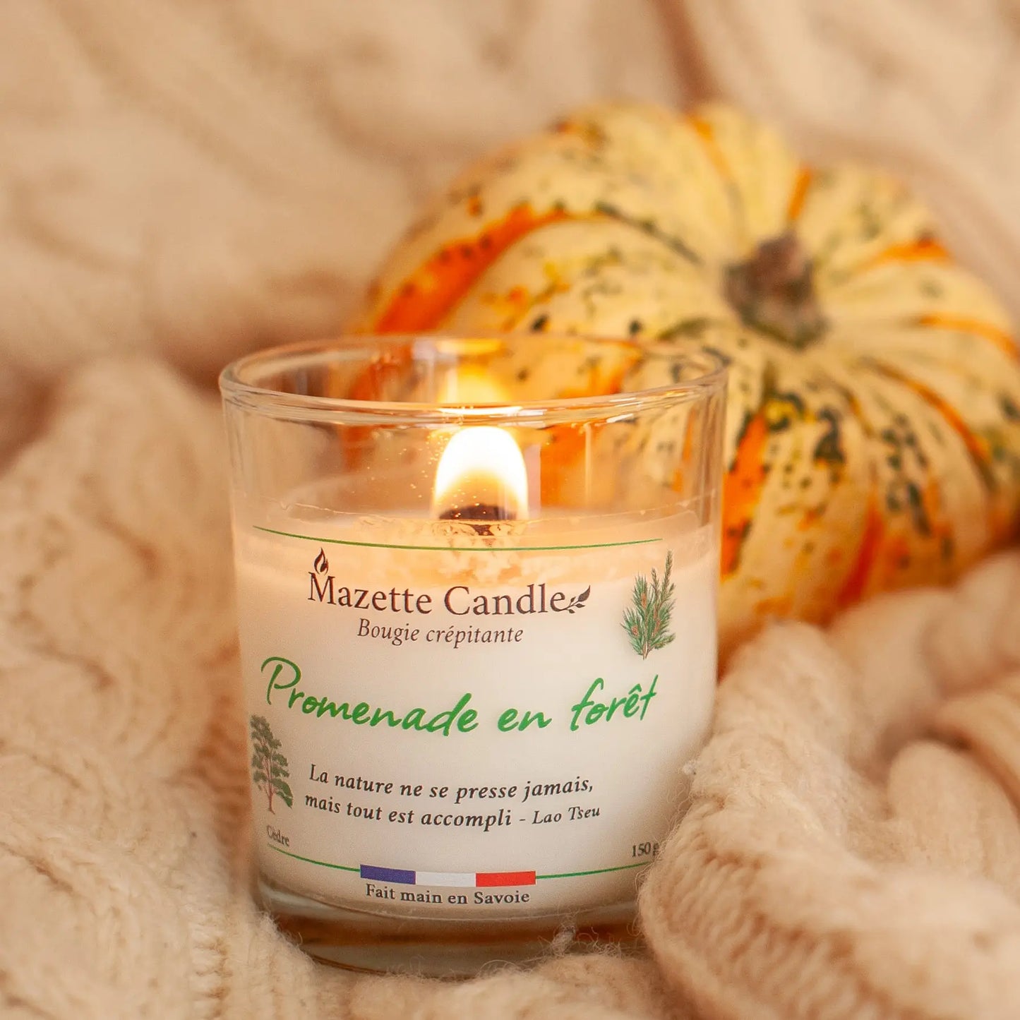 Bougie Mazette Candle Promenade en forêt 150g parfum cèdre, allumée dans un décor cocooning, une courge en arrière-plan
