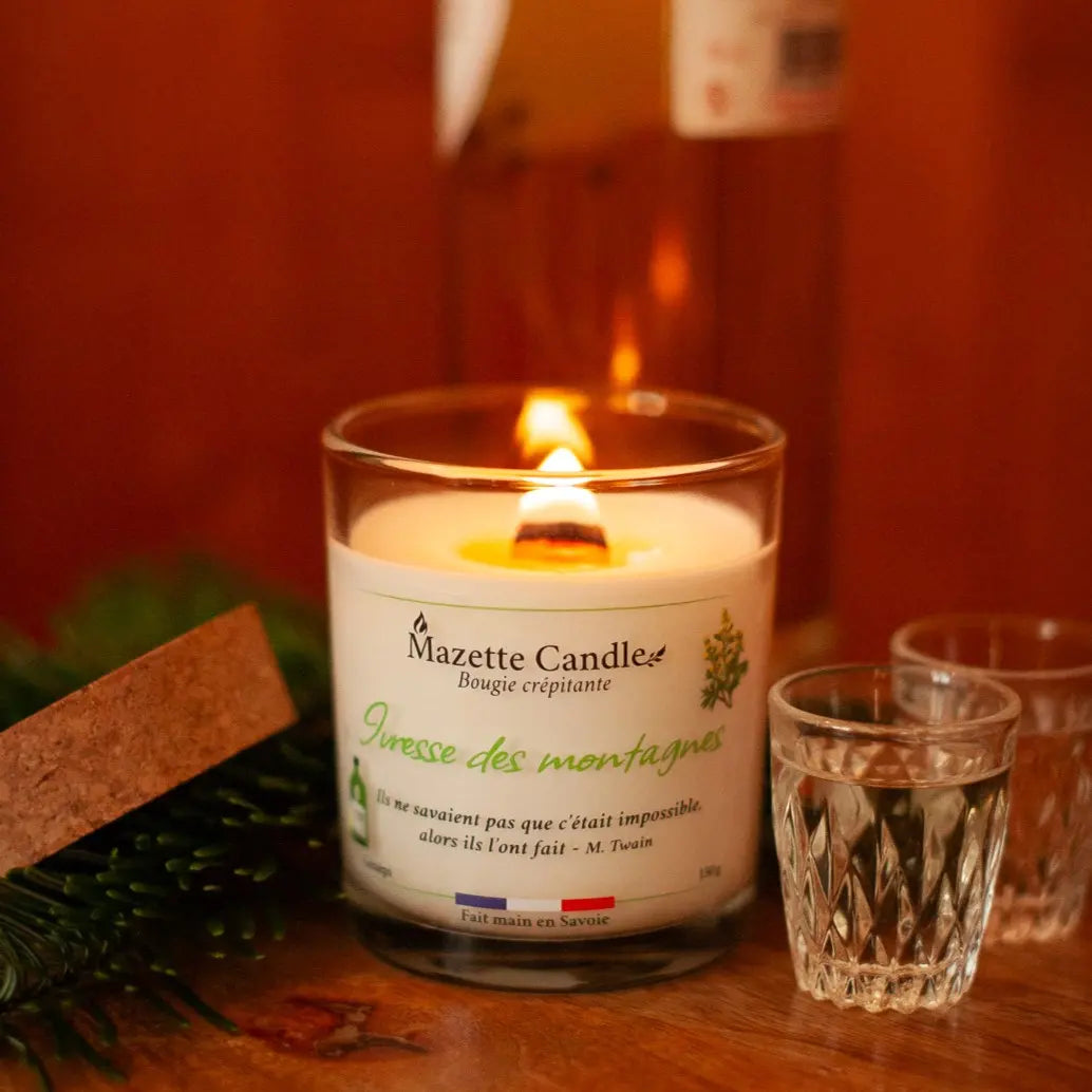 Bougie Mazette Candle Ivresse des montagnes 150g parfum génépi, allumée, avec son couvercle en liège et deux verres de génépi