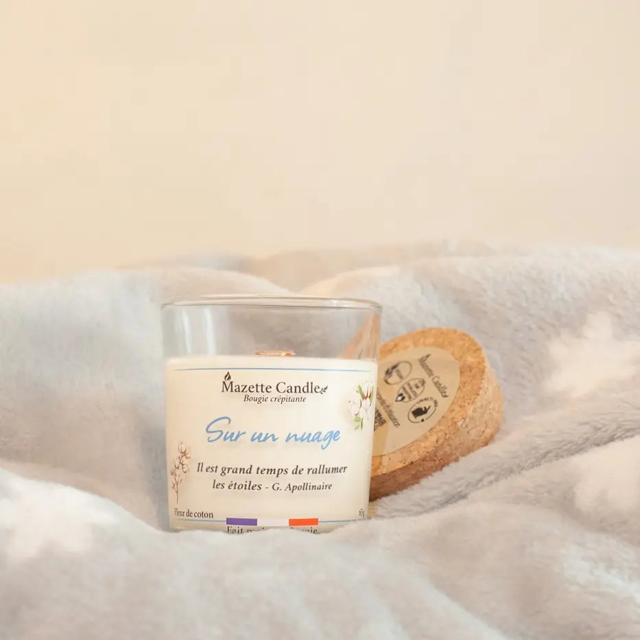 Bougie Mazette Candle Sur un nuage 65g parfum fleur de coton avec couvercle en liège, posée sur un plaid tout doux