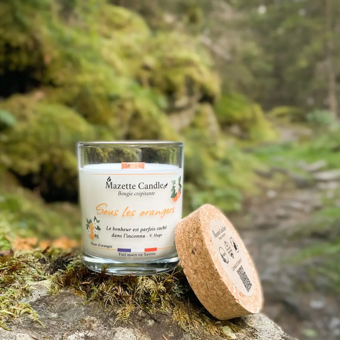 Bougie Mazette Candle Sous les orangers 150g parfum fleur d’oranger, sur un rocher en forêt, couvercle en liège posé à côté