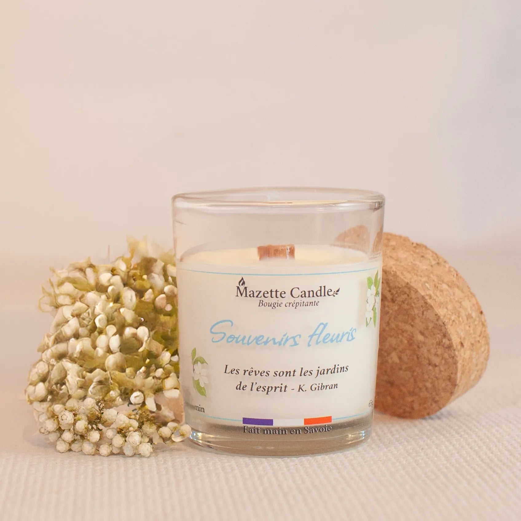 Bougie Mazette Candle Souvenirs fleuris 65g parfum jasmin, couvercle en liège posé à côté et petites fleurs blanches en décor