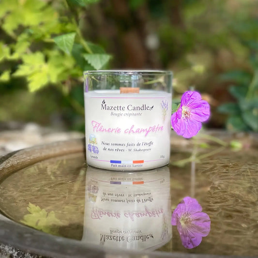 Bougie Mazette Candle Flânerie champêtre 150g parfum lavande, posée sur un plateau avec une fleur et se reflétant dans l’eau