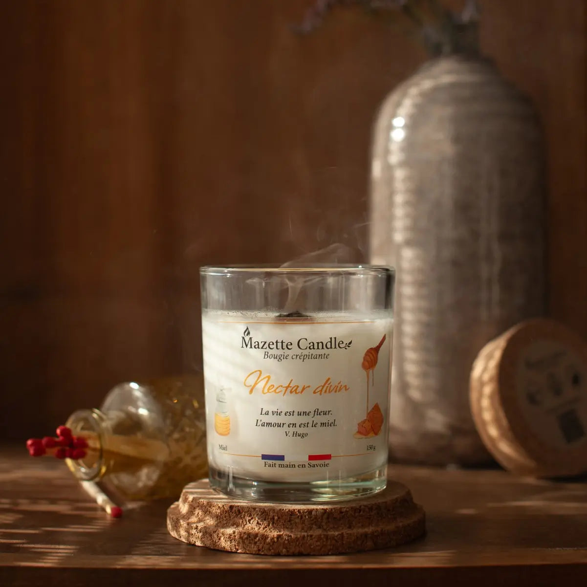Bougie Mazette Candle Nectar divin 150g parfum miel, tout juste éteinte, encore fumante sur son support en liège