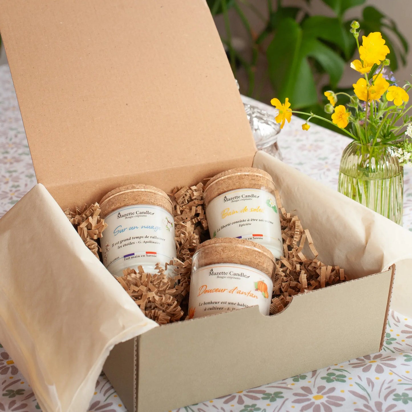 Boîte cadeau ouverte avec 3 bougies artisanales Mazette Candle 65g prêtes à offrir, avec bouquet de fleurs jaunes en décor