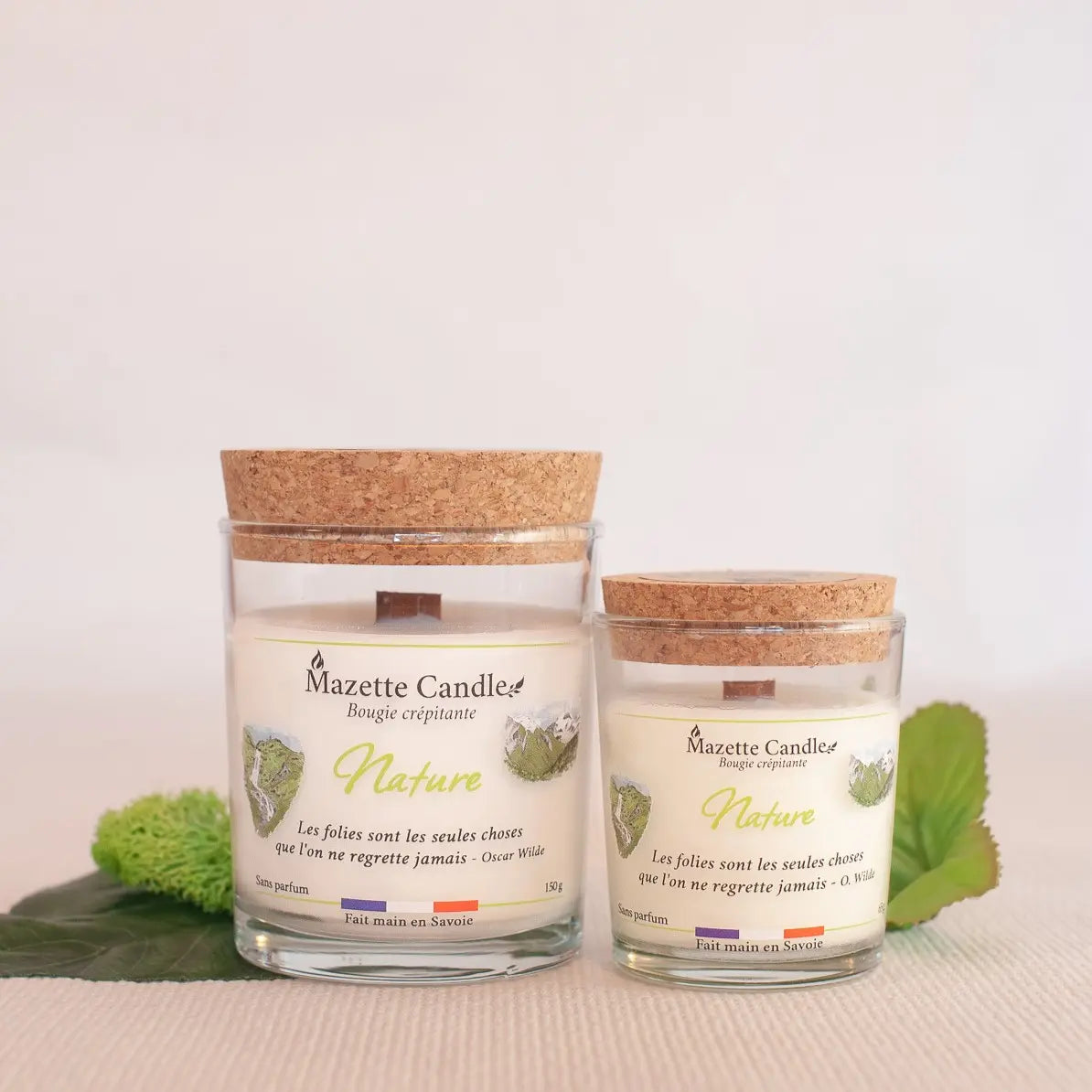 Deux bougies Mazette Candle Nature 65g et 150g sans parfum, avec leurs couvercles en liège, sur décor végétal